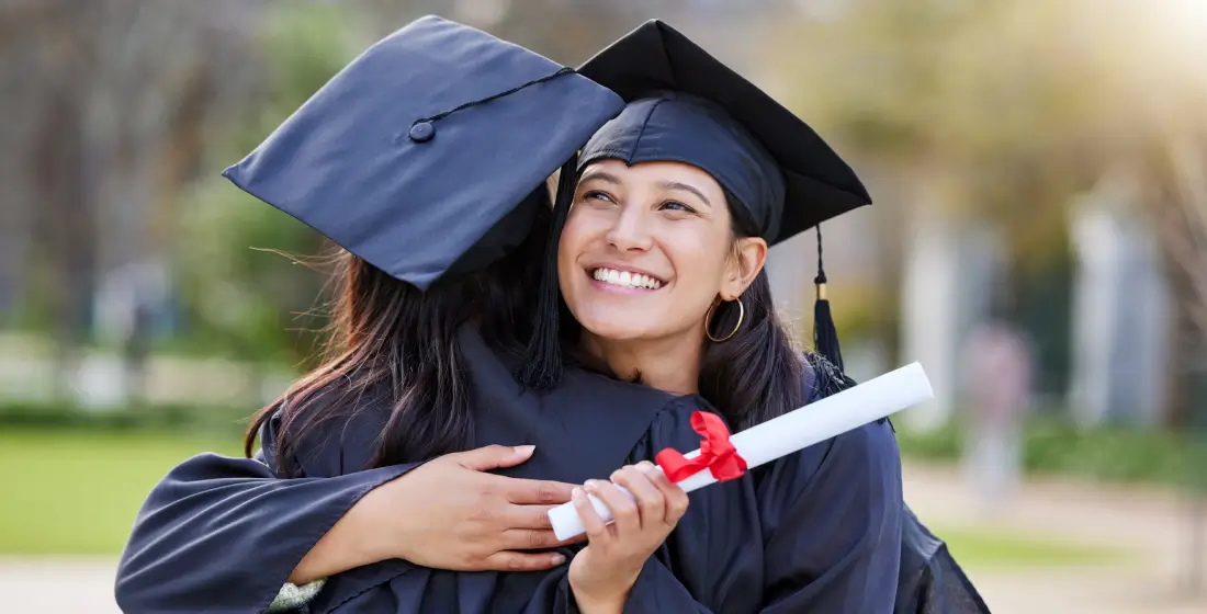 friends embracing on graduation day in caps and gowns