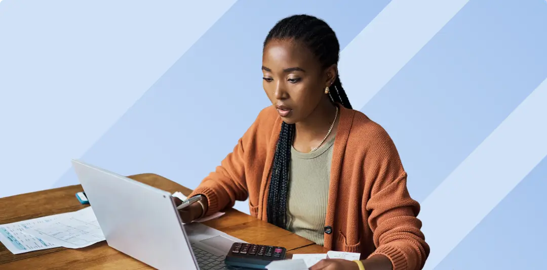 Young female entrepreneur checking financial documents and invoices while working on a laptop computer