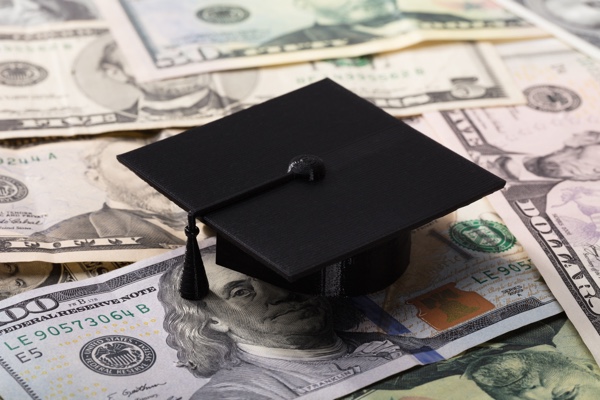 Graduation cap on top of bills of money