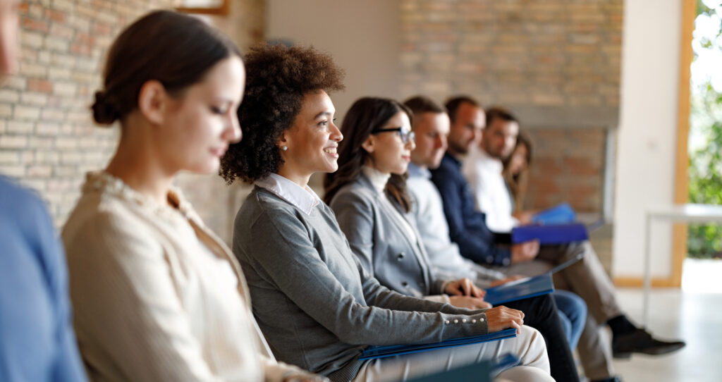 Men and women sit in a row waiting for job interview.