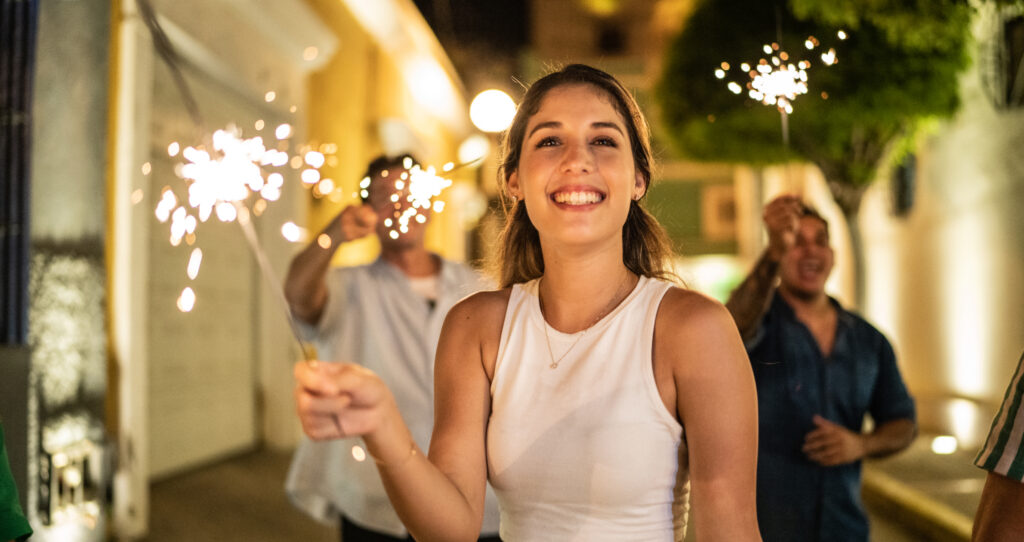 Woman smiles at camera holding a sparkler