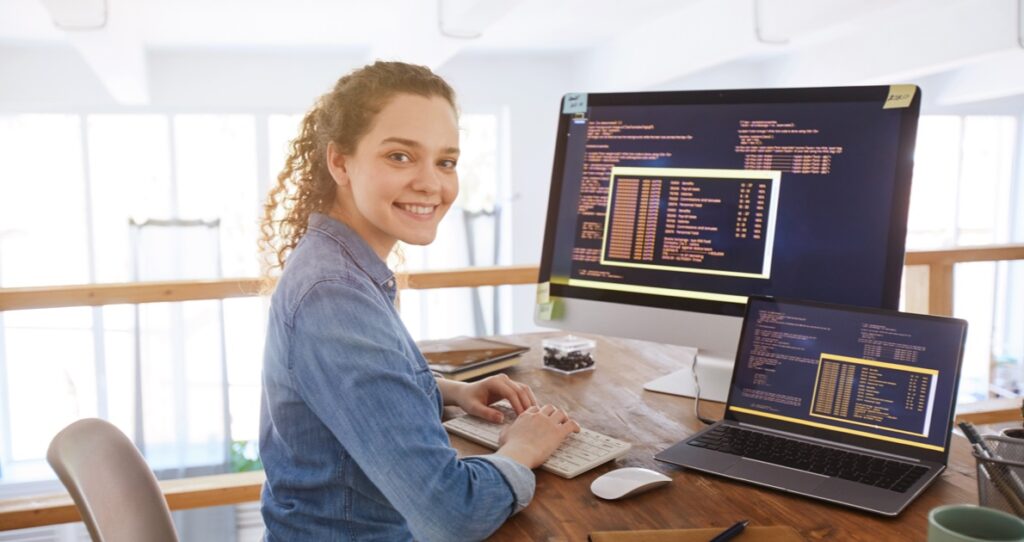 Student working at a desk with a laptop and computer monitor.