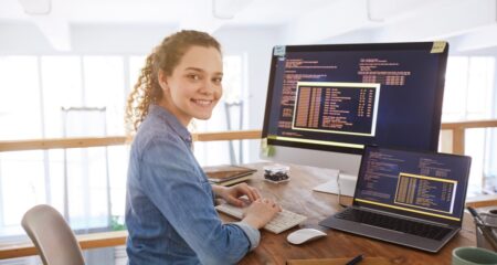 Student working at a desk with a laptop and computer monitor.