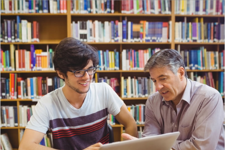 Two man looking at a laptop screen in a library