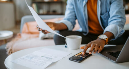 Man looks at papers and types into a calculator.