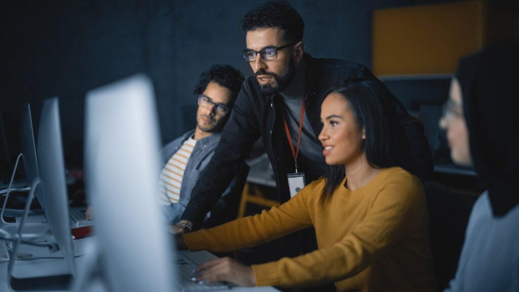 Teacher Giving Lesson to Diverse Group of Students in Software Engineering Bootcamp, Teaching New Skills on a Computer