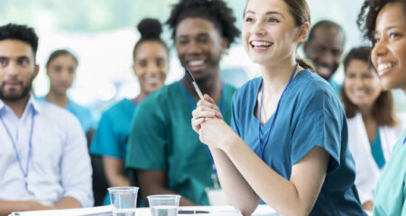 Cheerful female nursing students smiles as she listens to a professor's lecture.