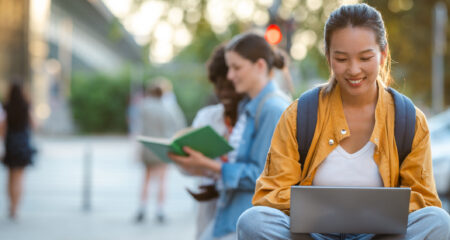 College student using a laptop outdoors while looking to improve their private student loan application.