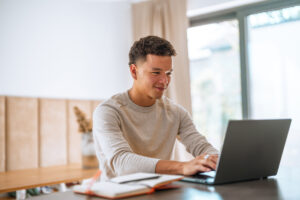 student looks on computer at private student loan features (beyond interest rate)