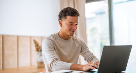 student looks on computer at private student loan features (beyond interest rate)