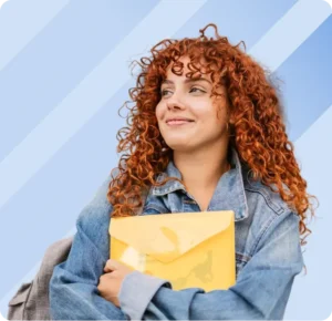 A smiling young woman with curly red hair wearing a denim jacket and holding a yellow plastic folder desktop learning what to do when When FAFSA Doesn’t Tell the Whole Story